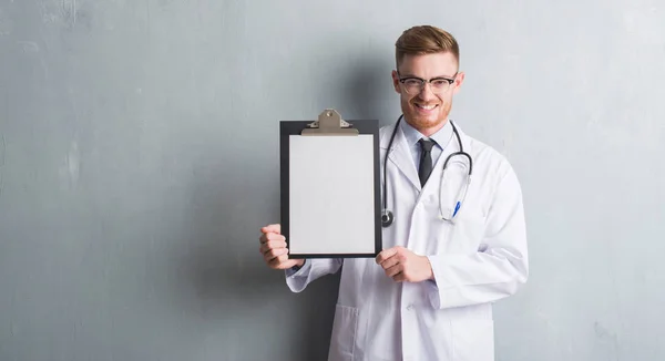 Jeune Rousse Médecin Homme Sur Gris Grunge Mur Tenant Presse — Photo