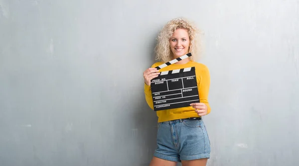 Joven Mujer Rubia Sobre Pared Gris Grunge Sosteniendo Calipboard Película — Foto de Stock