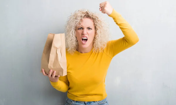 Young Blonde Woman Grunge Grey Background Holding Lunch Paper Bag — Stock Photo, Image