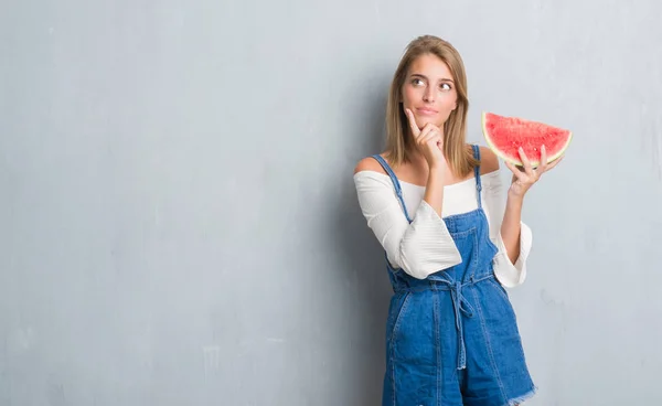 グランジ グレーの美しい若い女性壁に関する質問は 非常に混乱して考え食べる水メロン深刻な顔考えて — ストック写真