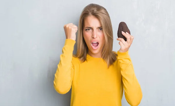 Schöne Junge Frau Über Grunge Graue Wand Essen Avocado Genervt — Stockfoto