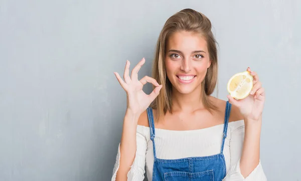 Hermosa Mujer Joven Sobre Pared Gris Grunge Sosteniendo Limón Haciendo —  Fotos de Stock