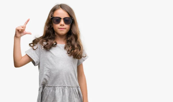 黑发西班牙裔女孩戴着太阳镜微笑着 自信的手势与手做尺寸标志 而在看和相机 度量概念 — 图库照片