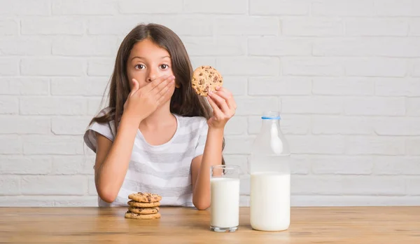 手でチョコレート クッキー カバー口を食べたり牛乳を飲むテーブルに座って若いヒスパニックの子供は間違い 沈黙の中 秘密の概念で怖いの表現のための恥とショックを受けた — ストック写真