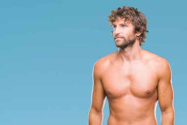 Yakışıklı İspanyol modeli adam seksi ve gömleksiz uzak tarafına yüzünde, doğal ifade gülümseme ile seyir izole arka plan üzerinde. Kendine güvenen gülüyor.