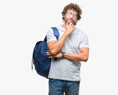Sırt çantası ve gözlük üzerinde giyen yakışıklı İspanyol öğrenci adam arka plan çene düşünme hakkında soru, dalgın ifade üzerine el ile izole. Düşünceli yüzüyle gülümsüyor. Şüphe kavramı.
