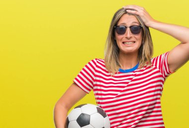 Baş, el ile vurguladı izole arka plan üzerinde futbol futbol topu tutan genç güzel kadın şok utanç ve sürpriz suratla, öfkeli ve sinirli. Korku ve hata için üzgün.