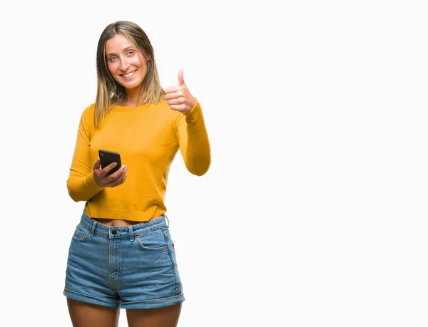 年轻美丽的女人发送消息使用智能手机在孤立的背景下快乐的大微笑做 拇指与手指 优秀的标志 — 图库照片