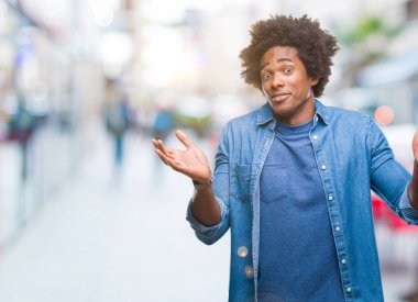 İzole arka plan clueless ve şaşkın bir ifadeyle kollar ve eller kaldırdı Afro Amerikan adam. Şüphe kavramı.