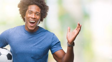 Afro Amerikalı adam futbol topu tutan kocaman bir gülümseme ile çığlık zaferini kutluyor ve ellerini kaldırdı arka plan çok mutlu ve heyecanlı, kazanan ifade izole