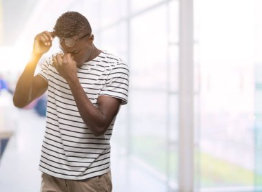 Gözlük ve lacivert t-shirt yorgun sürtünme burun ve göz yorgunluğu ve baş ağrısı duygu giyen genç Afro-Amerikan adam. Stres ve hayal kırıklığı kavramı.