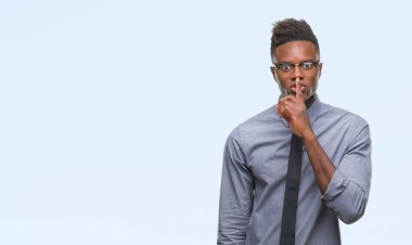 Dudaklarında parmak ile sessiz olmanı izole arka plan üzerinde genç Afro-Amerikalı iş adamı. Sessizlik ve gizli kavramı.