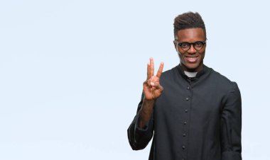 Genç Afro-Amerikan rahip adam gösterilen ve parmakları ile işaret izole arka plan üzerinde üçüncü ise kendinden emin ve mutlu gülümseyerek.