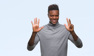 Gösterilen ve parmakları ile işaret izole arka plan üzerinde genç Afro-Amerikan adam kendinden emin ve mutlu gülümseyerek süre sekiz numara.