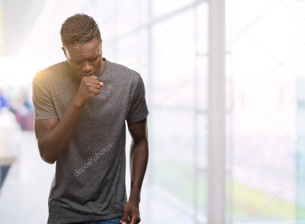 Young african american man wearing grey t-shirt feeling unwell and coughing as symptom for cold or bronchitis. Healthcare concept.
