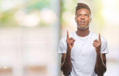 Genç Afro-Amerikan adam izole arka plan üzerinden hayran ve yukarıya bakıp parmakları ile işaret şaşırttı ve silah kaldırdı.