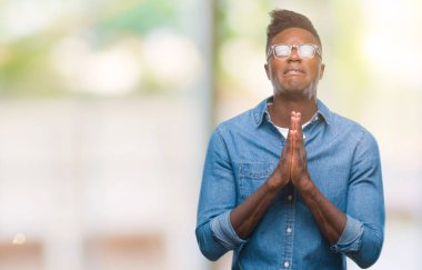 Afrikalı-Amerikalı genç yalvarıyor ve umut ifade yüzünde çok duygusal ve endişe ile birlikte elleriyle dua izole arka plan üzerinde. Bağışlanmak. Din kavramı.