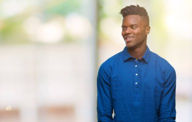 Afrikalı-Amerikalı genç uzak tarafına yüzünde, doğal ifade gülümseme ile seyir izole arka plan üzerinde. Kendine güvenen gülüyor.