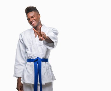 İzole arka plan giyen kimono zafer işareti yapıyor parmak gösterilen kamera seyir gülümseyen genç Afro-Amerikan adam. İki numaralı.
