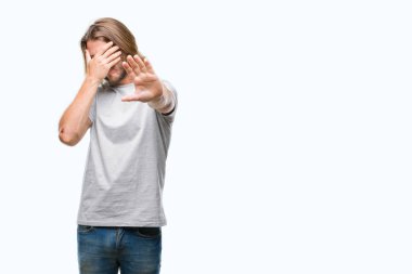 Üzerinde uzun saçlı yakışıklı delikanlı izole elleriyle gözlerini kapsayan arka plan ve stop jest ile acı ve korku ifadesi. Utandım ve negatif kavramı.