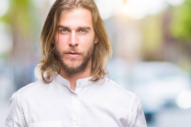Yüzünde ciddi bir ifade ile izole arka plan üzerinde uzun saçlı Genç yakışıklı adam. Basit ve doğal kameraya bakıyor.