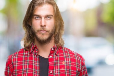 Yüzünde ciddi bir ifade ile izole arka plan üzerinde uzun saçlı Genç yakışıklı adam. Basit ve doğal kameraya bakıyor.
