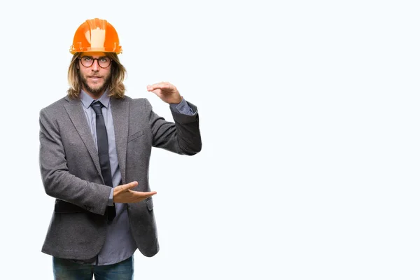年轻英俊的建筑设计男子长头发戴安全帽在孤立的背景手势与手显示大和大尺寸标志 测量符号 微笑着看着相机 测量概念 — 图库照片