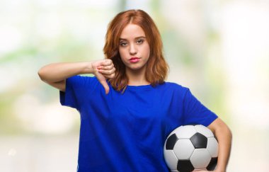 Genç güzel kadın futbol futbol topuyla kızgın yüzü, eksi işareti aşağı antipati başparmak ile gösterilen, ret kavramı holding izole arka plan üzerinde