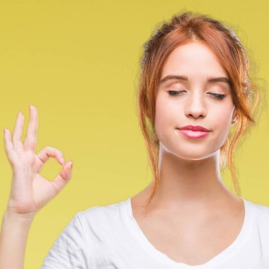 Genç güzel kadın izole arka plan üzerinde dinlenmek ve gülümseyen gözlerle parmak ile meditasyon jest yapıyor kapalı. Yoga kavramı.