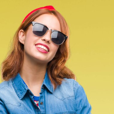 İzole arka çapraz silah kameraya bakarak ile gülümseyen güneş gözlüğü mutlu yüz giyen genç güzel kadın. Olumlu bir kişi.