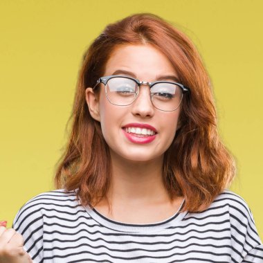 Genç güzel kadın kutluyor gözlük takan izole arka plan yüzünden şaşırttı ve silah ile başarı için yükseltilmiş ve açık gözler hayrete düşürdü. Kazanan kavramı.