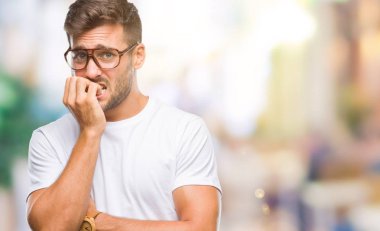 Genç yakışıklı adam stresli ve gergin ile izole arka plan üzerinde gözlük takan tırnak ısırma dudaklarından eller. Anksiyete sorunu.