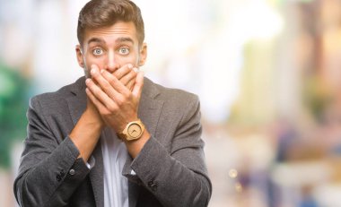 Genç yakışıklı iş adamı izole arka plan ağız hata için elleriyle kapsayan şok içinde. Gizli kavramı.