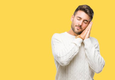 Uyku yorgun hayal ve ellerle birlikte poz ile kapalı gözler gülümseyen izole arka plan üzerinde kış kazak giyen genç yakışıklı adam.