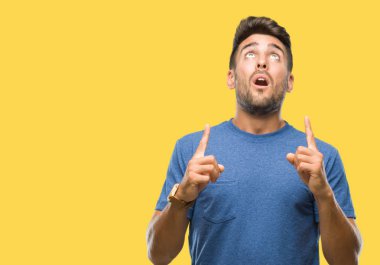 Yakışıklı delikanlı izole arka plan üzerinden hayran ve yukarıya bakıp parmakları ile işaret şaşırttı ve silah kaldırdı.