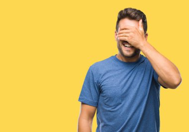 Yakışıklı genç gülümseyen ve gözler için sürpriz kapsayan yüz el ile gülüyor izole arka plan üzerinde. Kör kavramı.