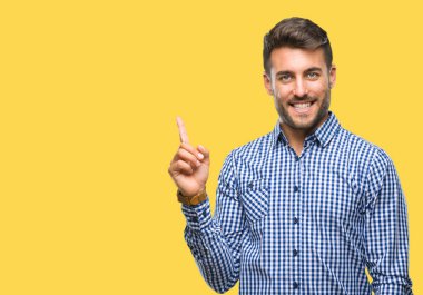 Kameraya bakarak yan el ve parmak ile işaret eden genç yakışıklı adam yüzünde kocaman bir gülümseme ile izole arka plan üzerinde.