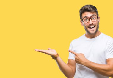 Hayret ve el ile sunulması ve parmak ile işaret ederken kameraya gülümseyen izole arka plan üzerinde gözlük takan genç yakışıklı adam.