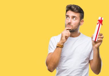 Sevgililer hediye izole arka plan ciddi bir yüz düşünme hakkında soru, çok karışık fikir üzerinden veren aşık genç yakışıklı adam