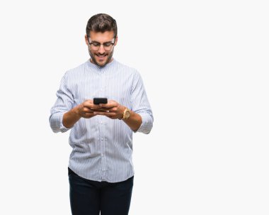 Yakışıklı delikanlı manifatura Smartphone izole arka plan üzerinde duran ve diş gösterilen kendine güvenen bir gülümsemeyle gülümseyerek mutlu bir yüz ile kullanma