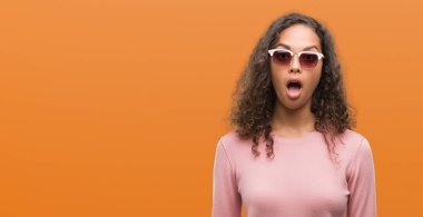 Güzel genç İspanyol kadın korkuyor ve şok sürpriz ifade, korku ve heyecan yüz ile güneş gözlüğü takıyor.