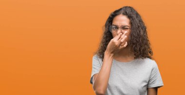 Bir şey pis ve iğrenç kokulu gözlük, dayanılmaz koku, holding nefes parmak ile burun üzerinde giyen güzel genç İspanyol kadın. Kötü kokuyor kavramı.