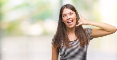 Genç güzel İspanyol kadın yapıyor gülümseyen telefon hareketi ile el ve parmak telefonda konuşuyor gibi. Kavramları iletişim.