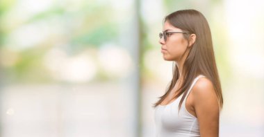 Genç güzel İspanyol yan, doğal yüz emin gülümseme ile pozuyla profil rahatla aramaya güneş gözlüğü takıyor.