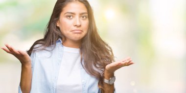 Genç güzel Arap kadın izole arka plan clueless ve şaşkın bir ifadeyle kollar ve eller kaldırdı. Şüphe kavramı.