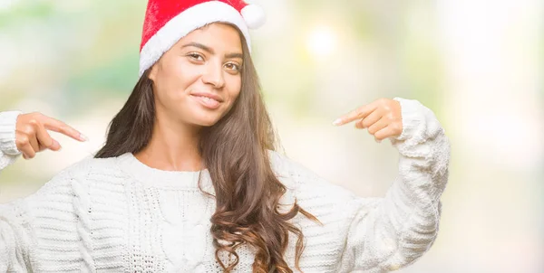 年轻的阿拉伯妇女戴着圣诞帽在孤立的背景下 脸上露出自信的笑容 用手指自豪和快乐地指着自己 — 图库照片