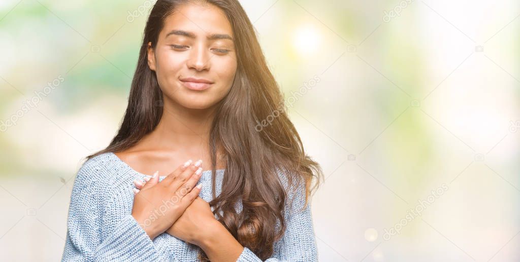 Young beautiful arab woman wearing winter sweater over isolated background smiling with hands on chest with closed eyes and grateful gesture on face. Health concept.