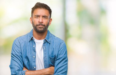 İzole arka plan şüpheci ve sinir, onaylamayan ifade yüz çapraz kolları olan yetişkin İspanyol adam. Negatif kişi.