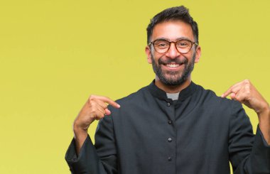 Yetişkin İspanyol Katolik rahip adam yüzünde gülümseme ile kendinden emin görünüyorsun, kendini gururlu ve mutlu parmakları ile işaret izole arka plan üzerinde.
