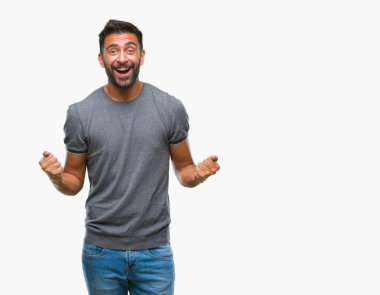 İzole arka plan kutlama üzerinde yetişkin İspanyol adam şaşırttı ve başarı için kaldırdı kollarını açarak hayret ve gözleri açık. Kazanan kavramı.